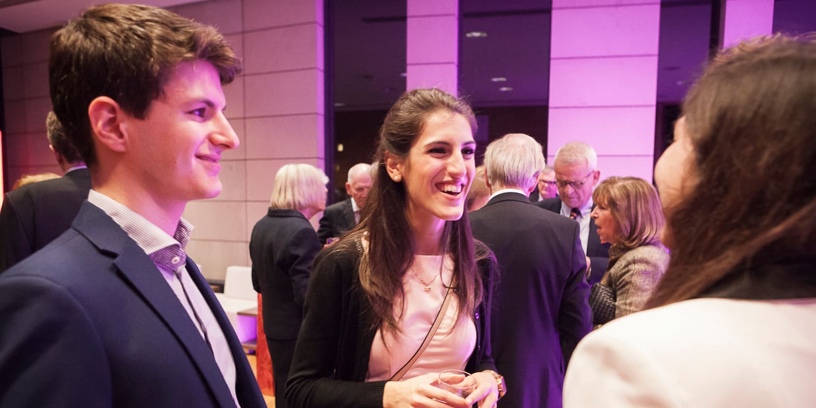 Two young adults conversing and laughing at a social event.