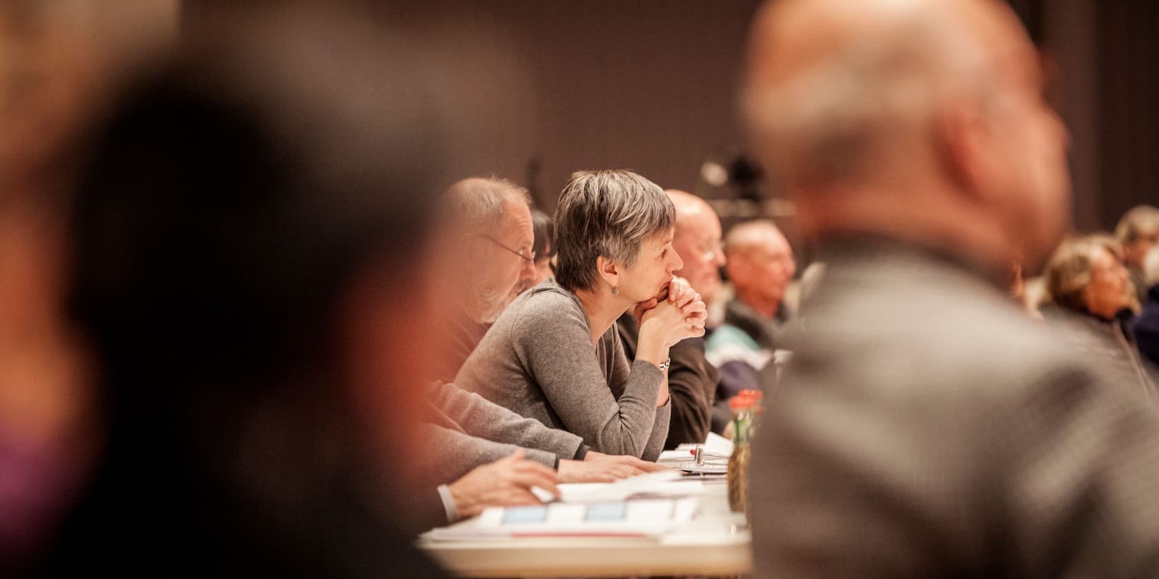 People focused on a presentation, taking notes.