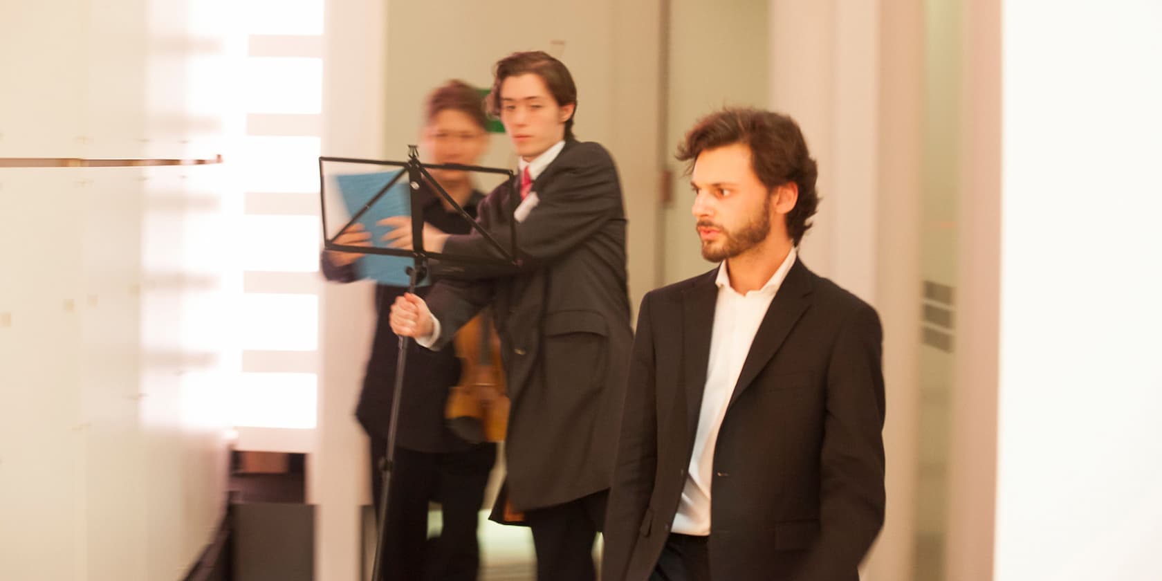 Two men in suits, one holding a music stand.