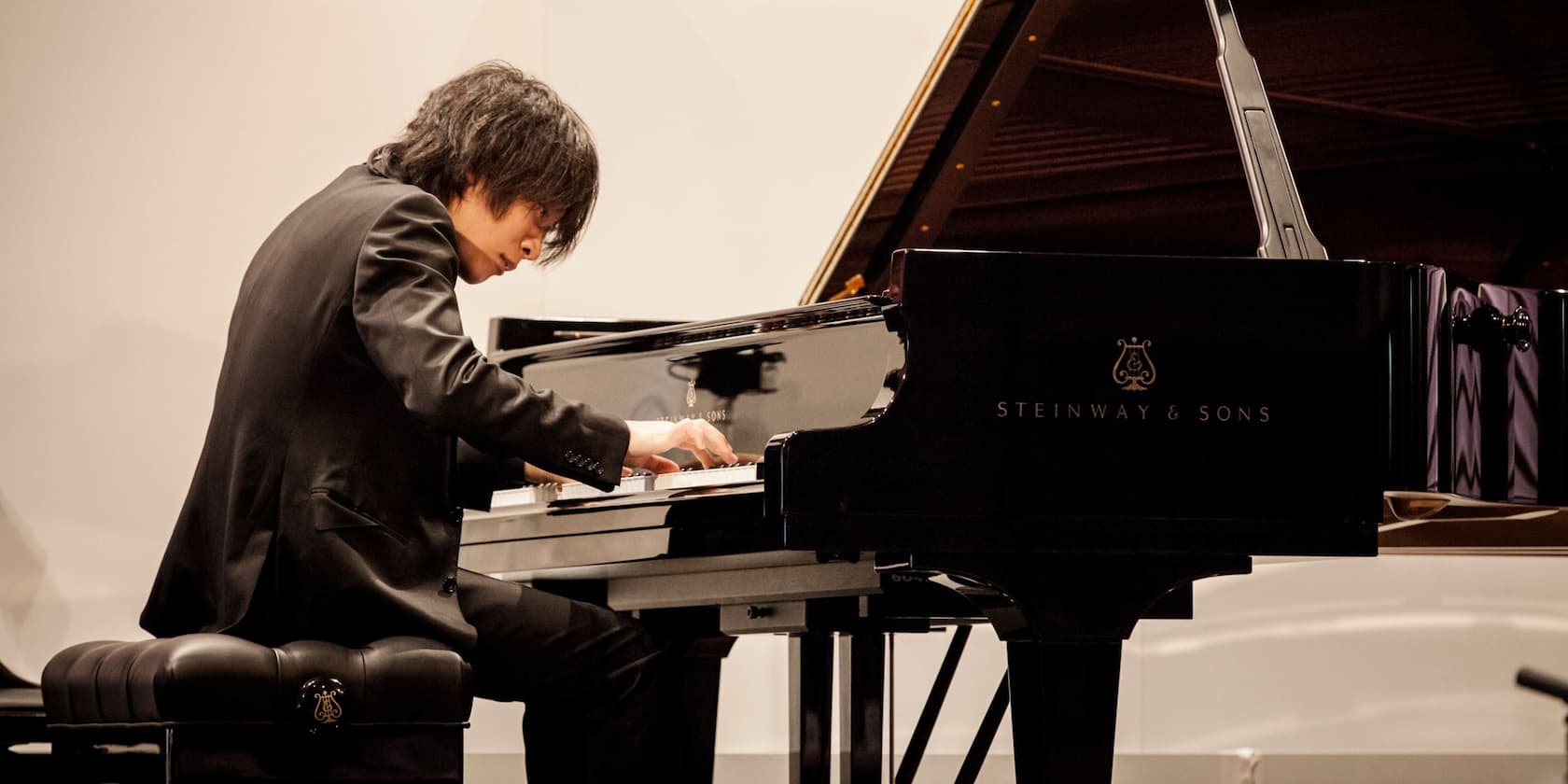 A man playing the piano on a Steinway & Sons grand piano.