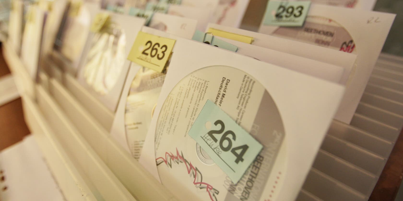 Close-up of a shelf with numbered CDs in paper sleeves.