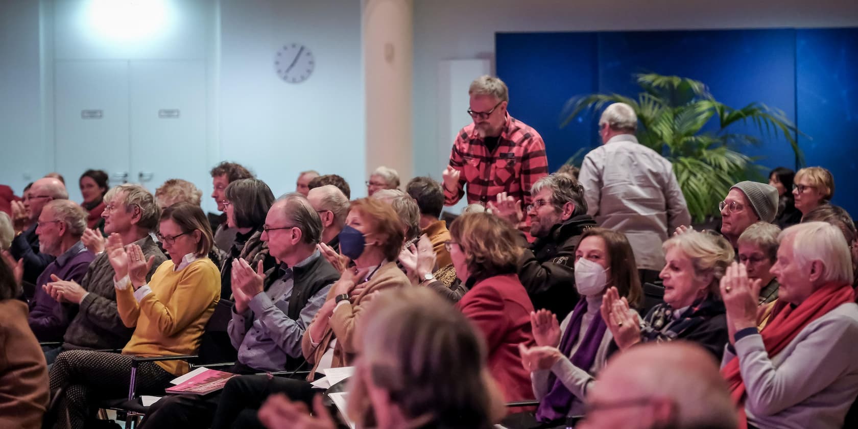 A group of people applauds in an event room.