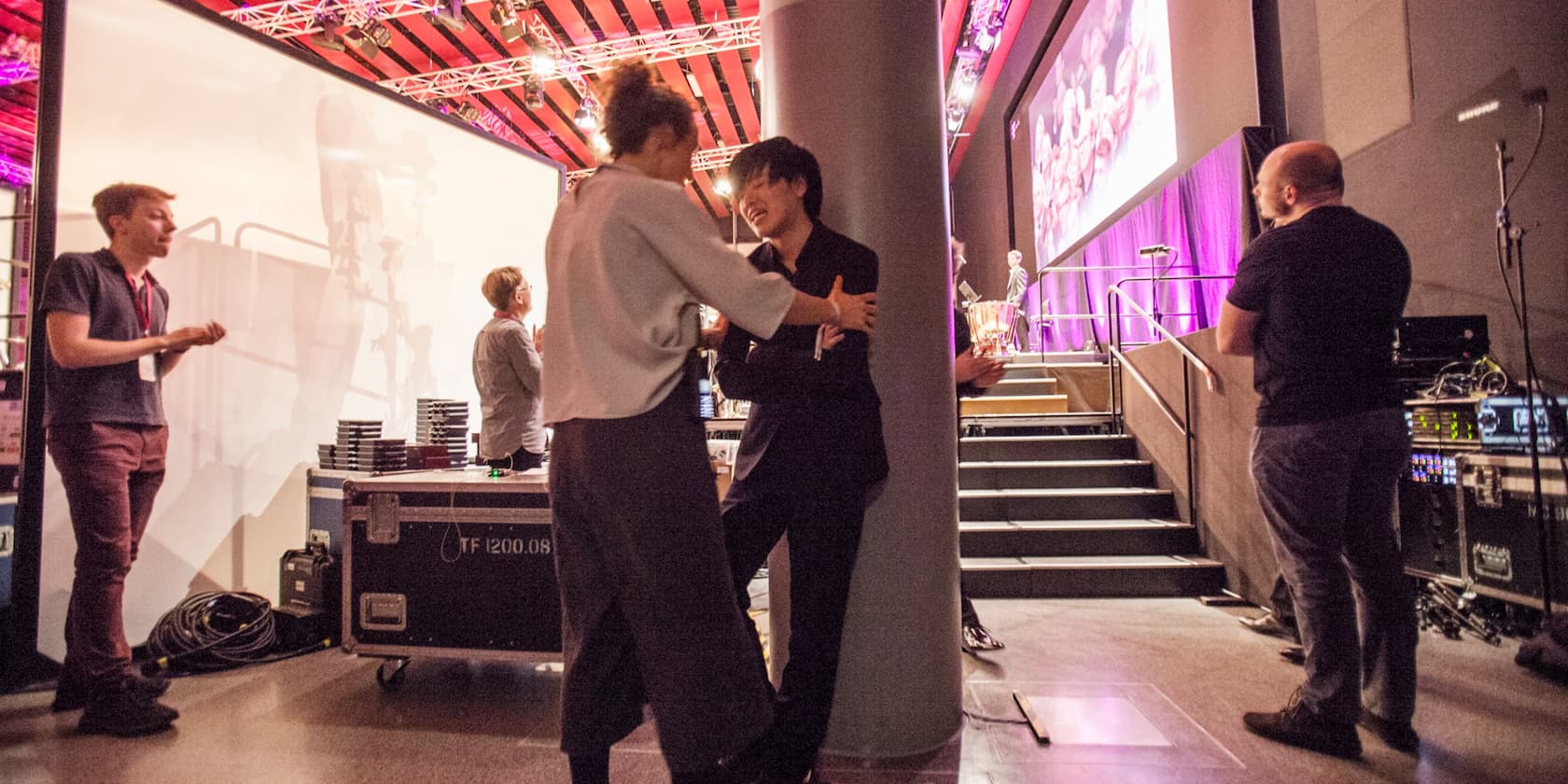 People working and chatting backstage at an event.