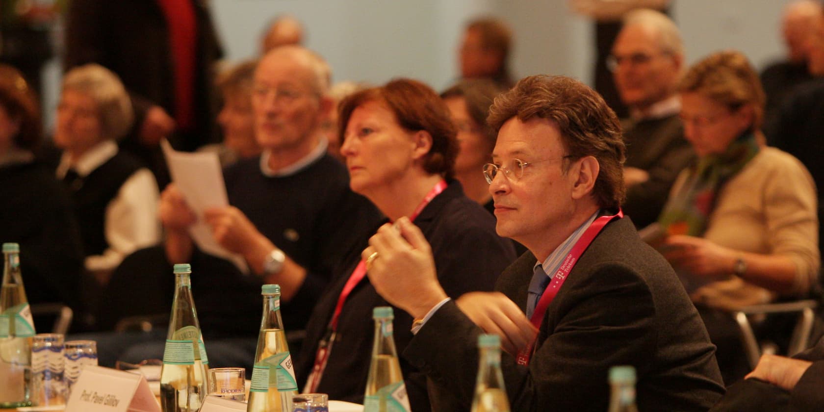 People attending a conference, some holding documents in their hands.