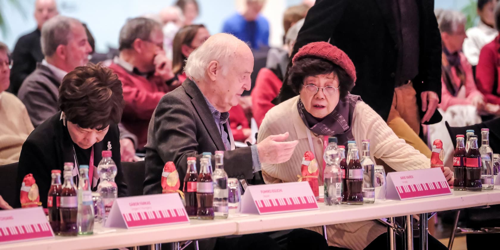 People sitting at a conference table and talking to each other. Drinks and name tags are on the table.