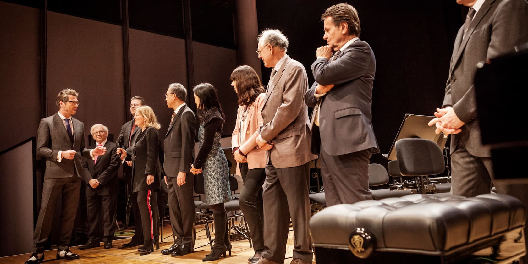 Several people in suits and formal attire standing on a stage, having a conversation.