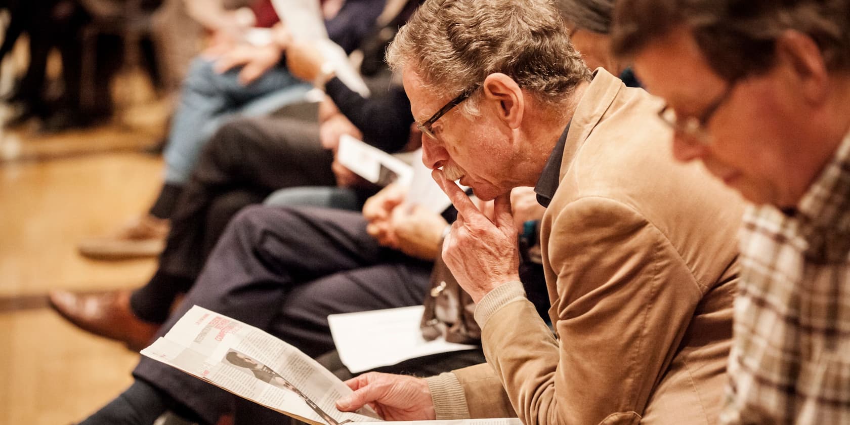 Older man attentively reading a document in a meeting.