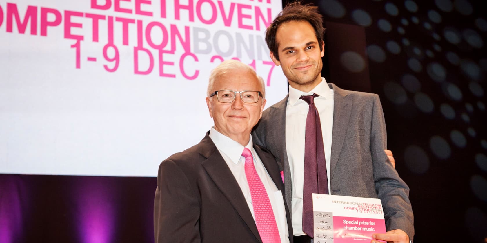 Zwei Männer posieren auf der Bühne der International Telekom Beethoven Competition Bonn 2017; einer hält eine Urkunde.