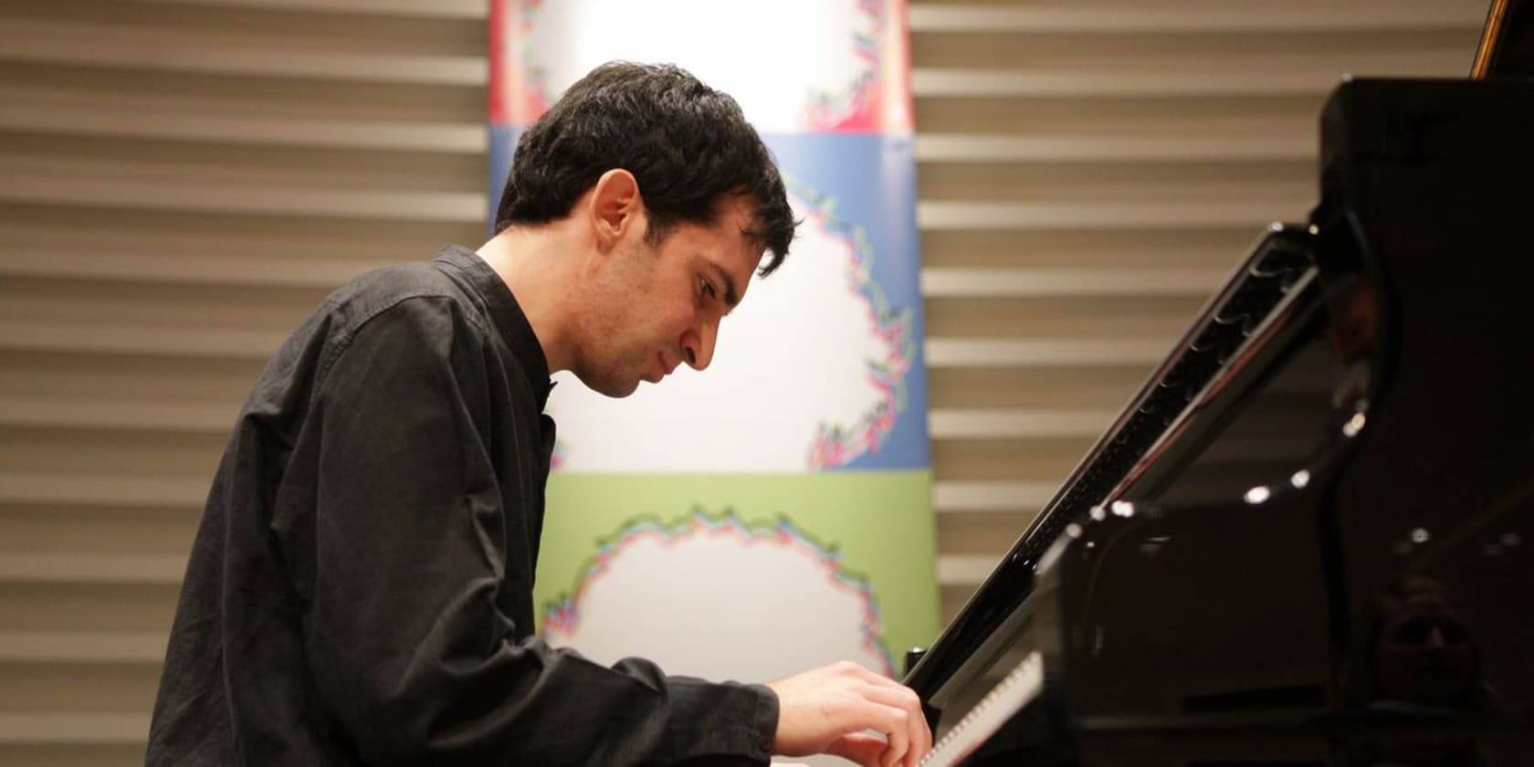 A man playing the piano in a room with decorative backgrounds.