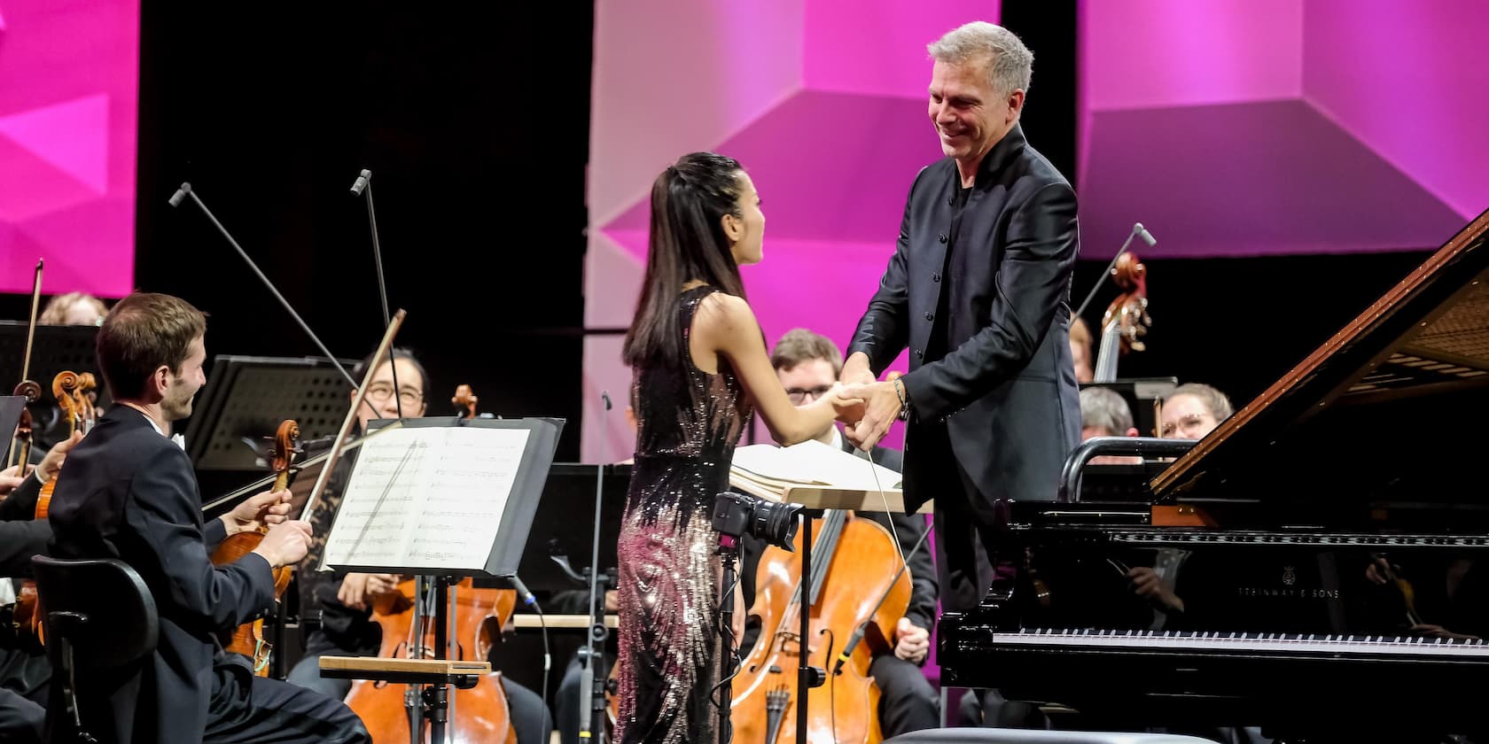 Conductor shaking hands with the soloist after an orchestral performance.