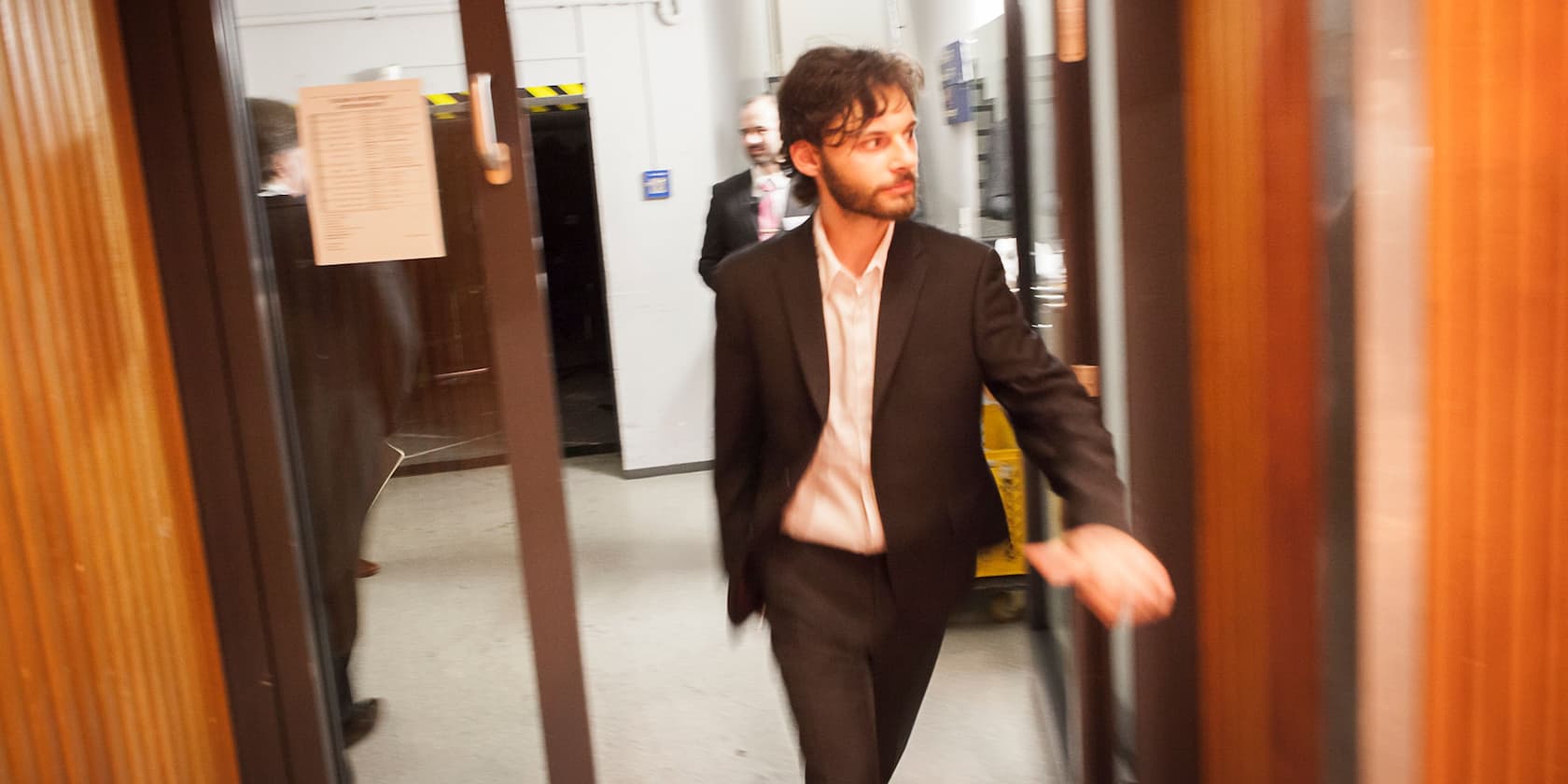 A man in a suit walking through a glass door in a building