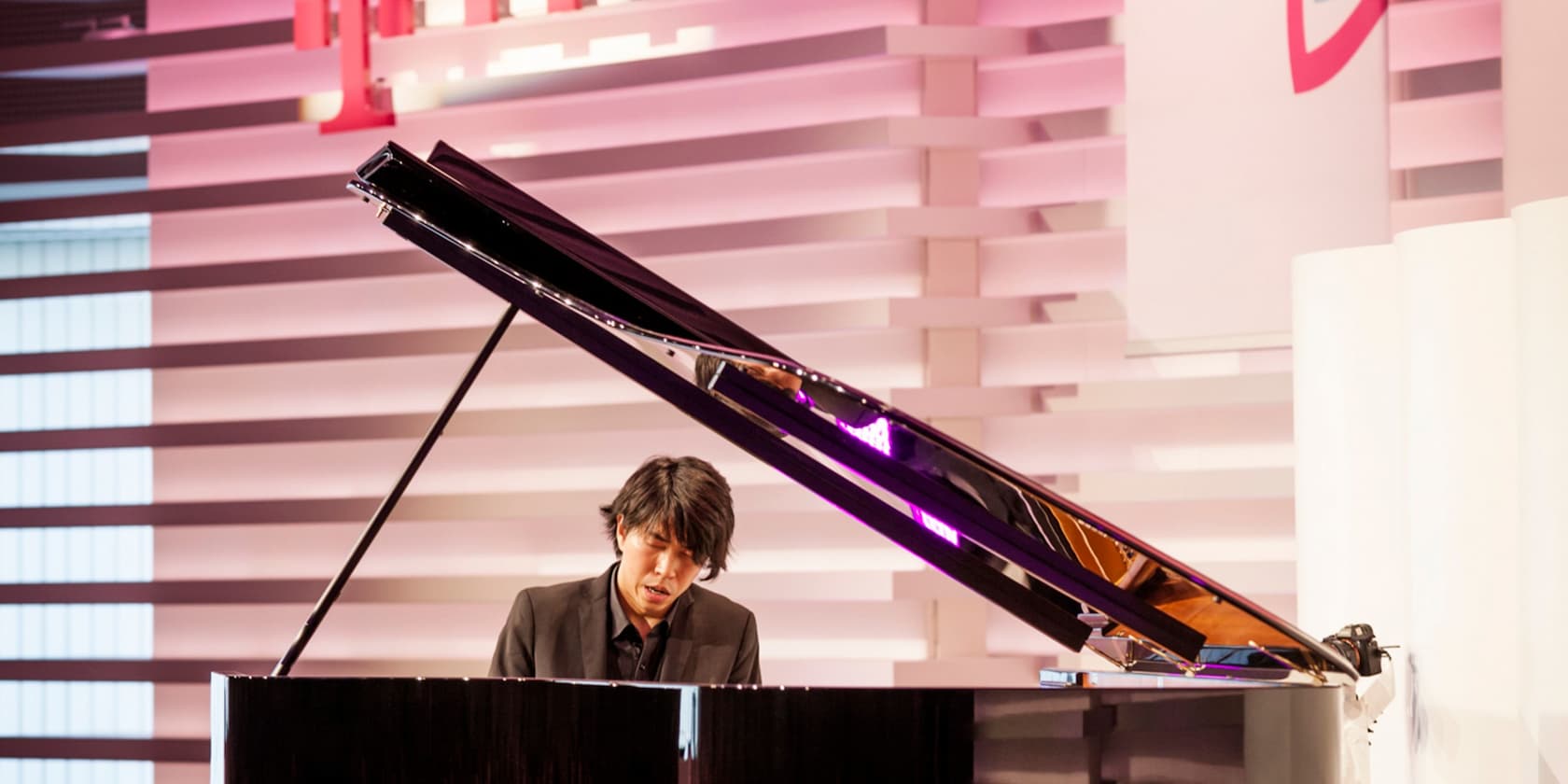 A man playing piano on a stage with a textured background.