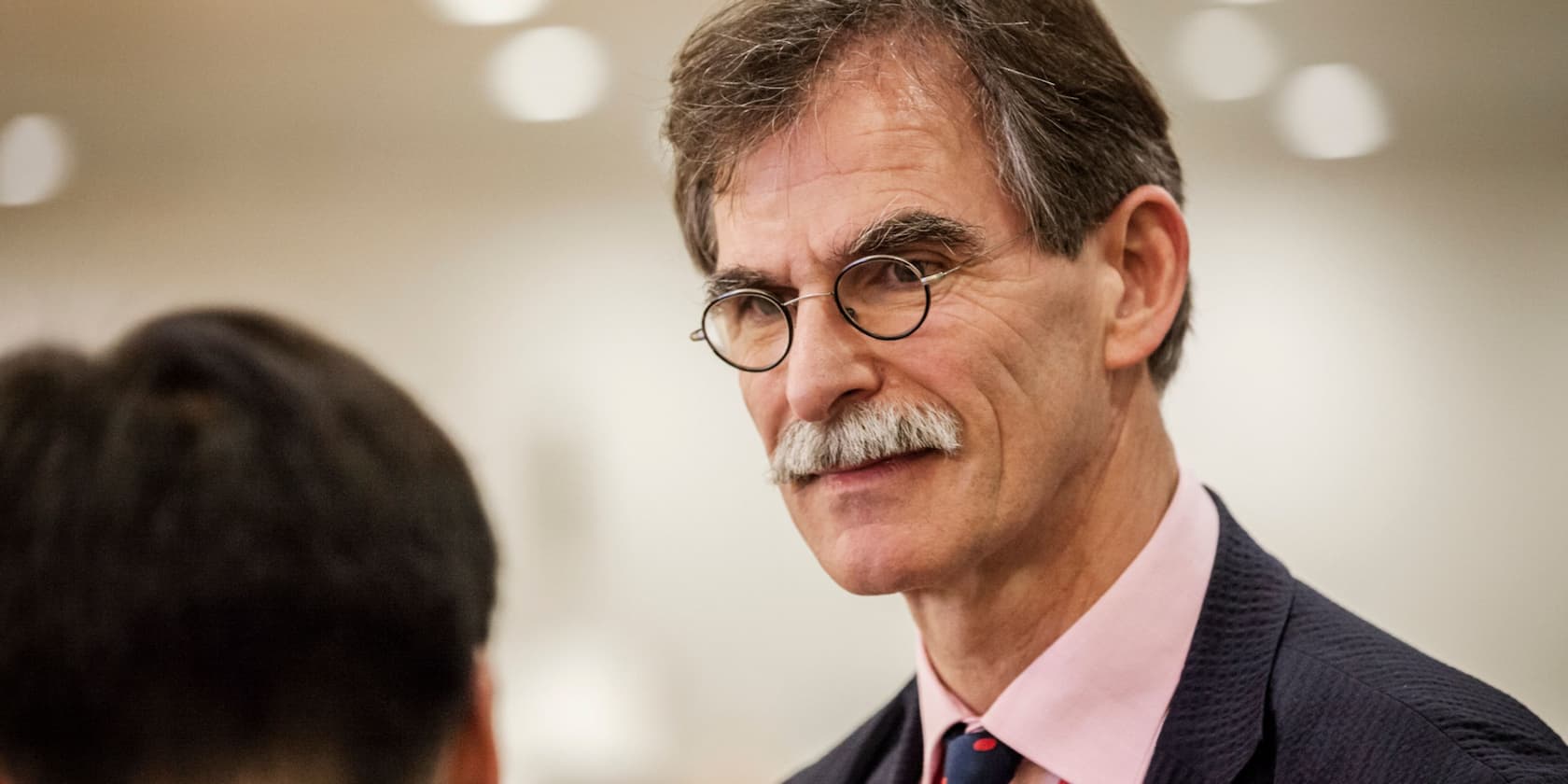 Man with glasses and mustache in a conversation