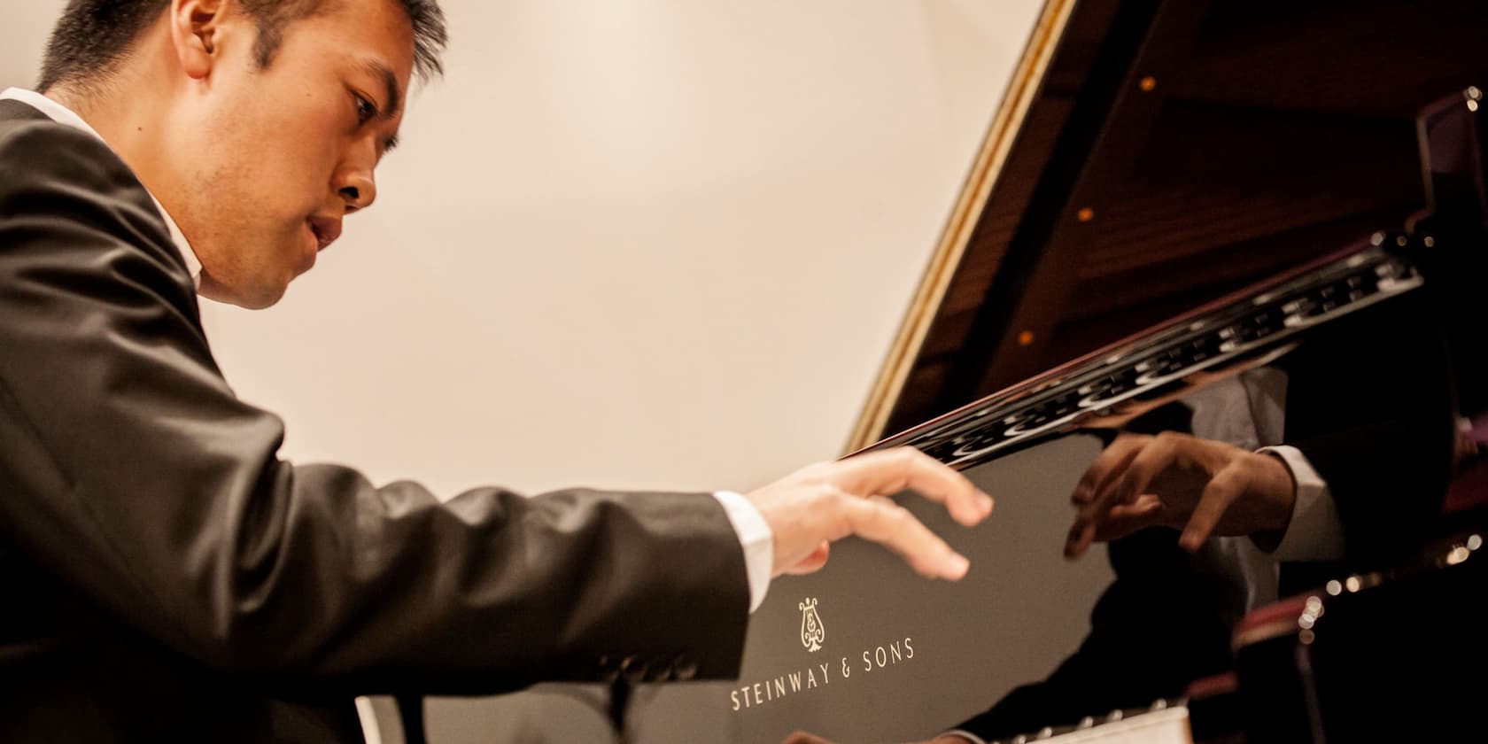 A man in a suit playing a Steinway & Sons piano.