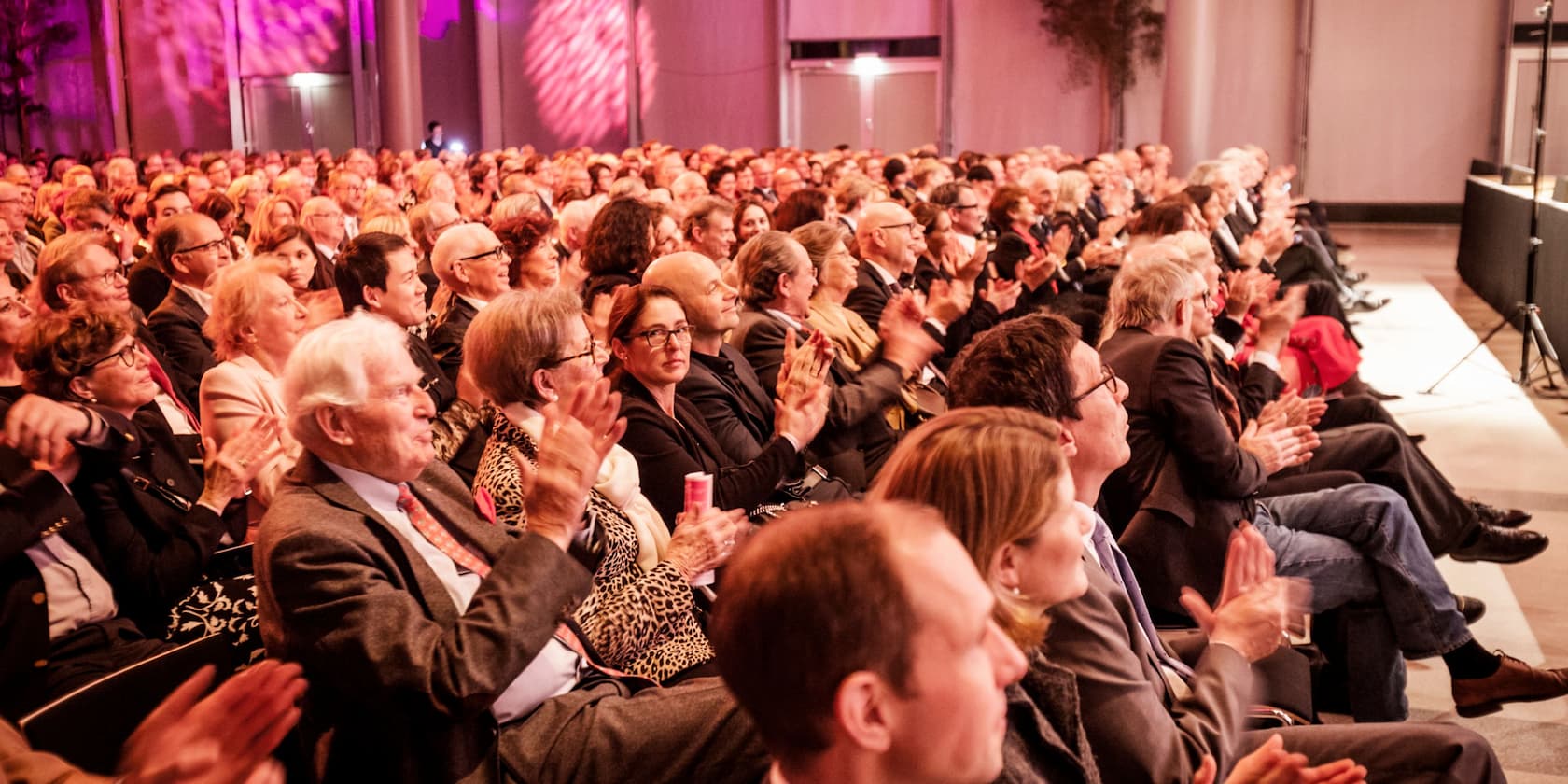 Large group of people clapping at an event.