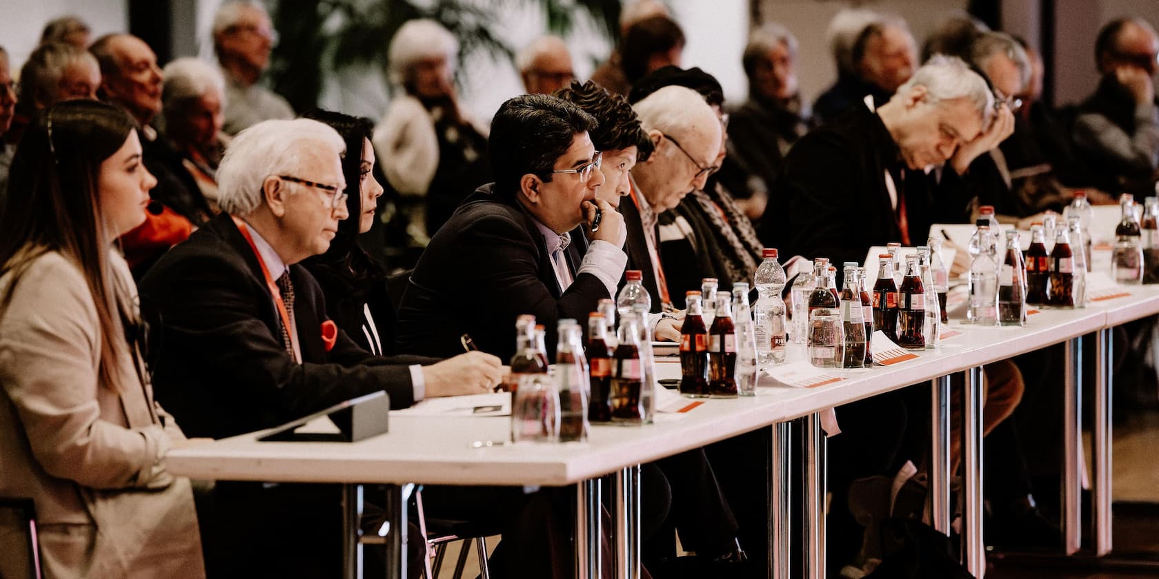 Menschen sitzen an einem Konferenztisch und hören aufmerksam zu.