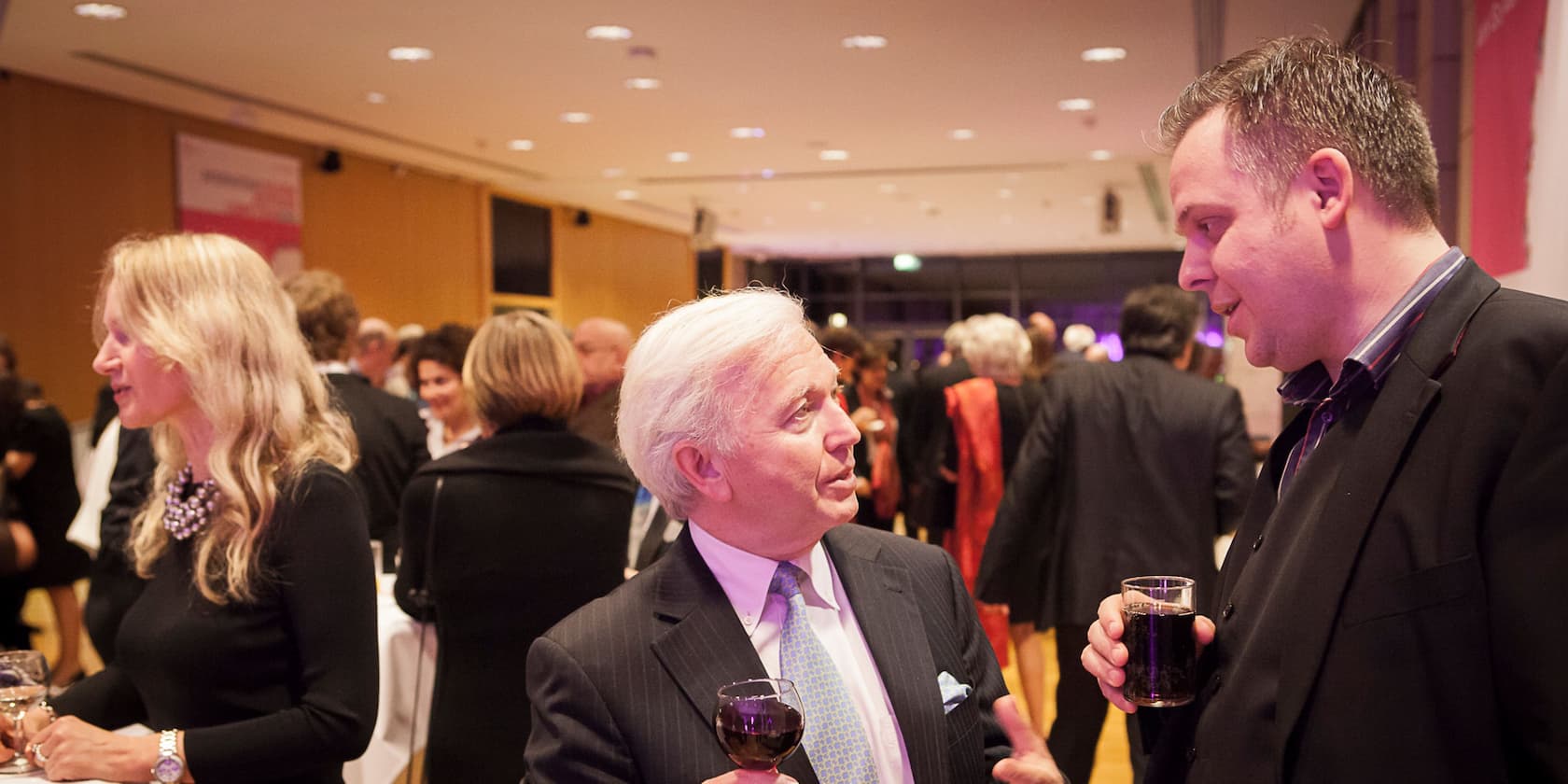 People at an evening event, conversing and holding drinks