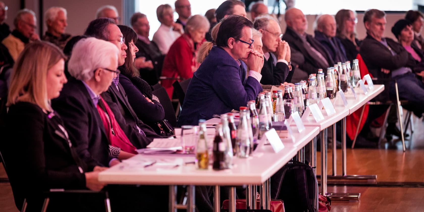 Gruppe von Menschen sitzt an Tischen während einer Konferenz.