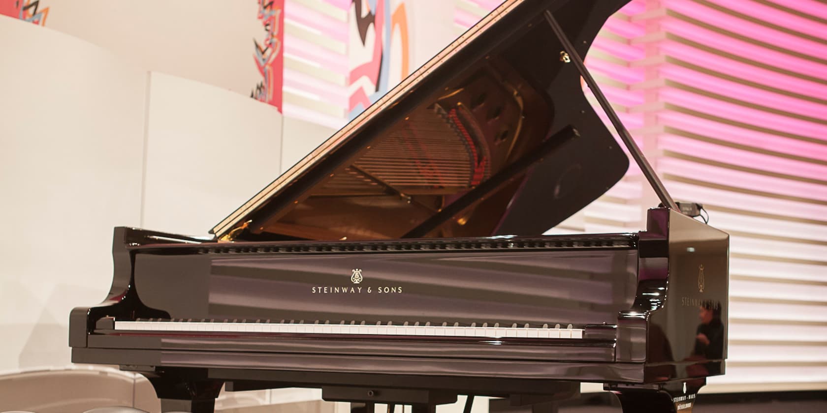 Grand piano by Steinway & Sons on a lit stage.