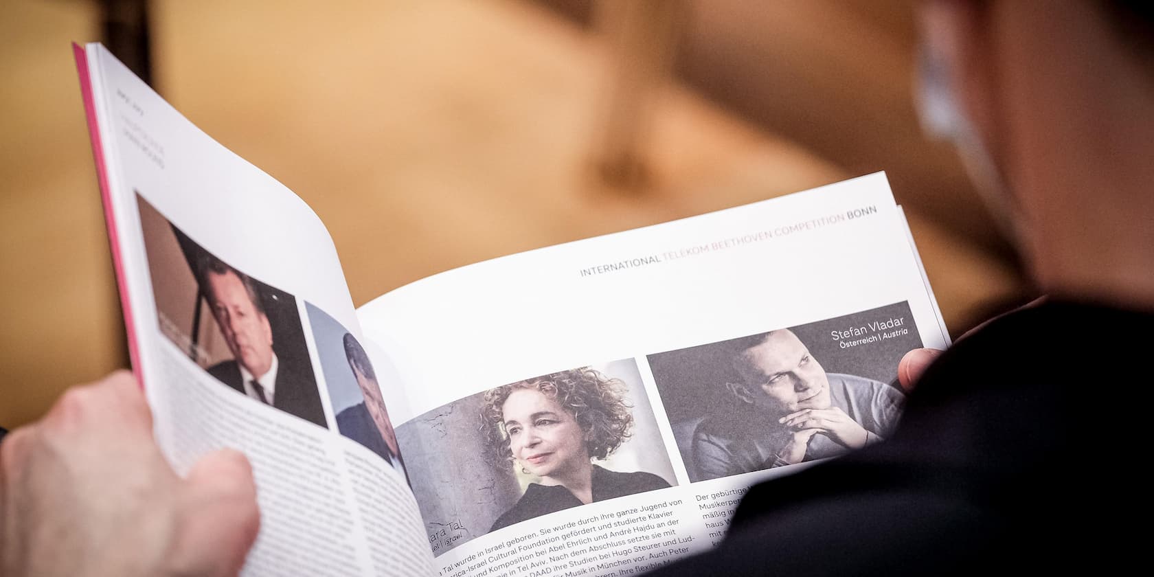 A person reads a brochure with pictures and short biographies of participants in the International Telekom Beethoven Competition in Bonn.