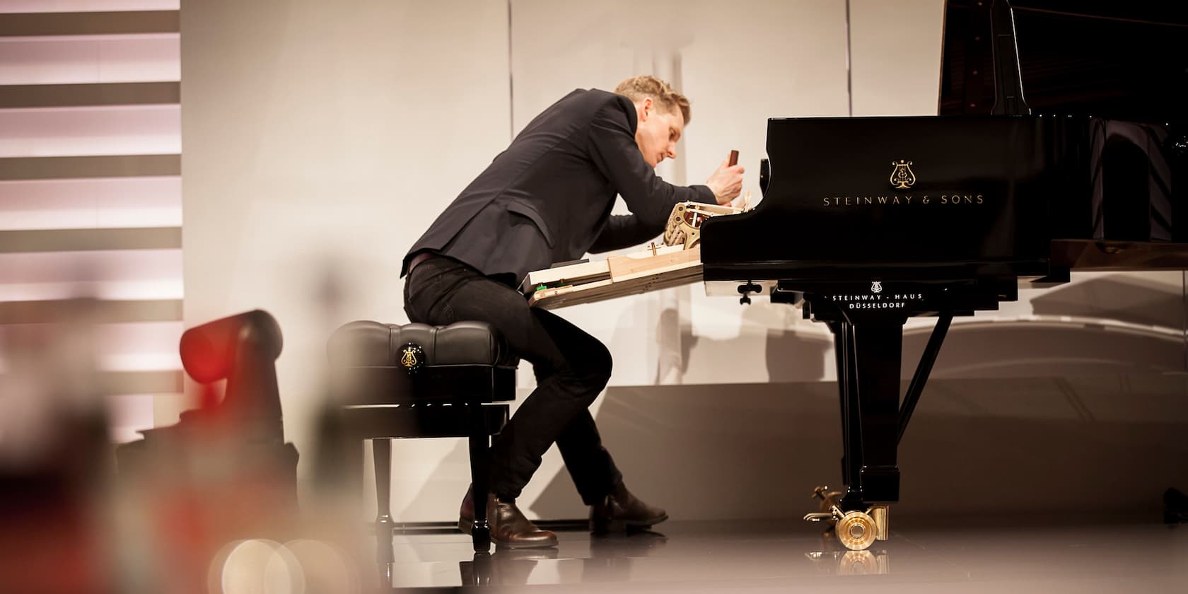 A man working on the inner mechanics of a Steinway & Sons grand piano.