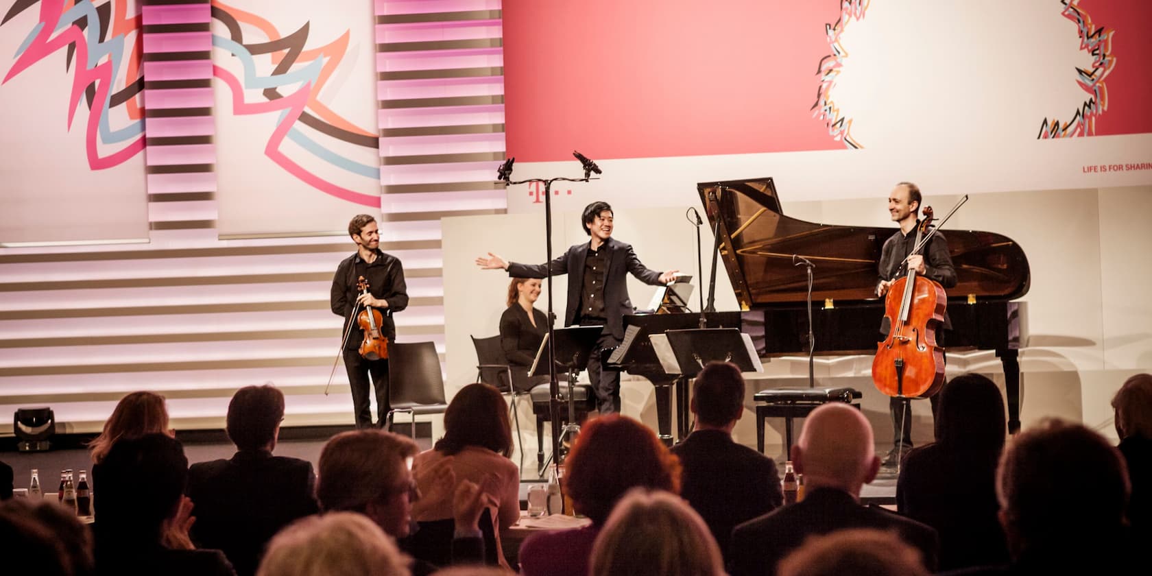 Musiker auf der Bühne bei einem Konzert während eines Events, vor einem applaudierendes Publikum.