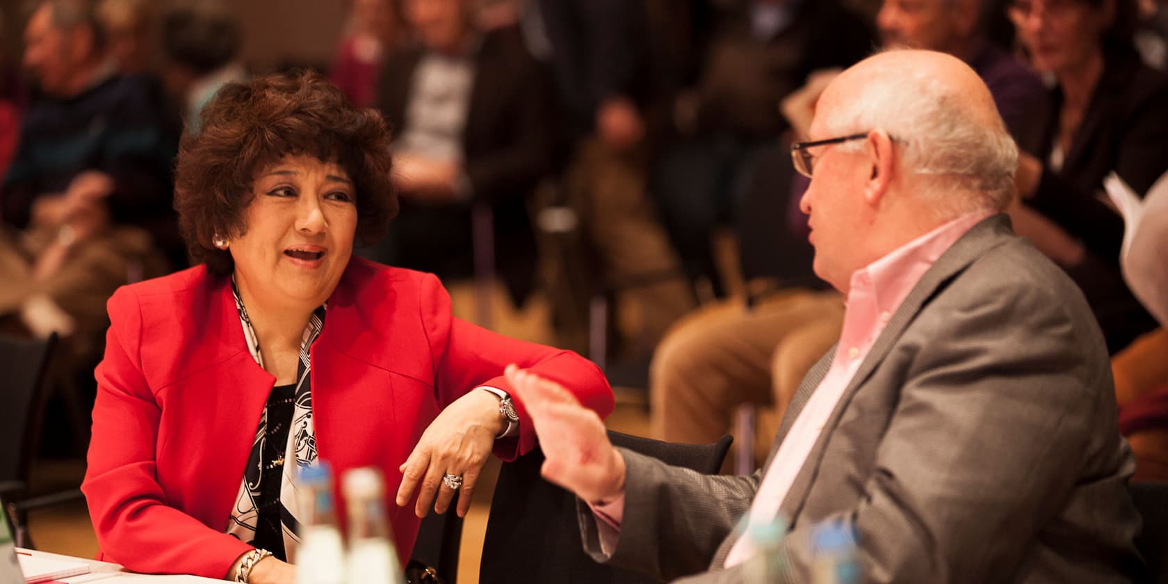 Two people conversing in a conference room.