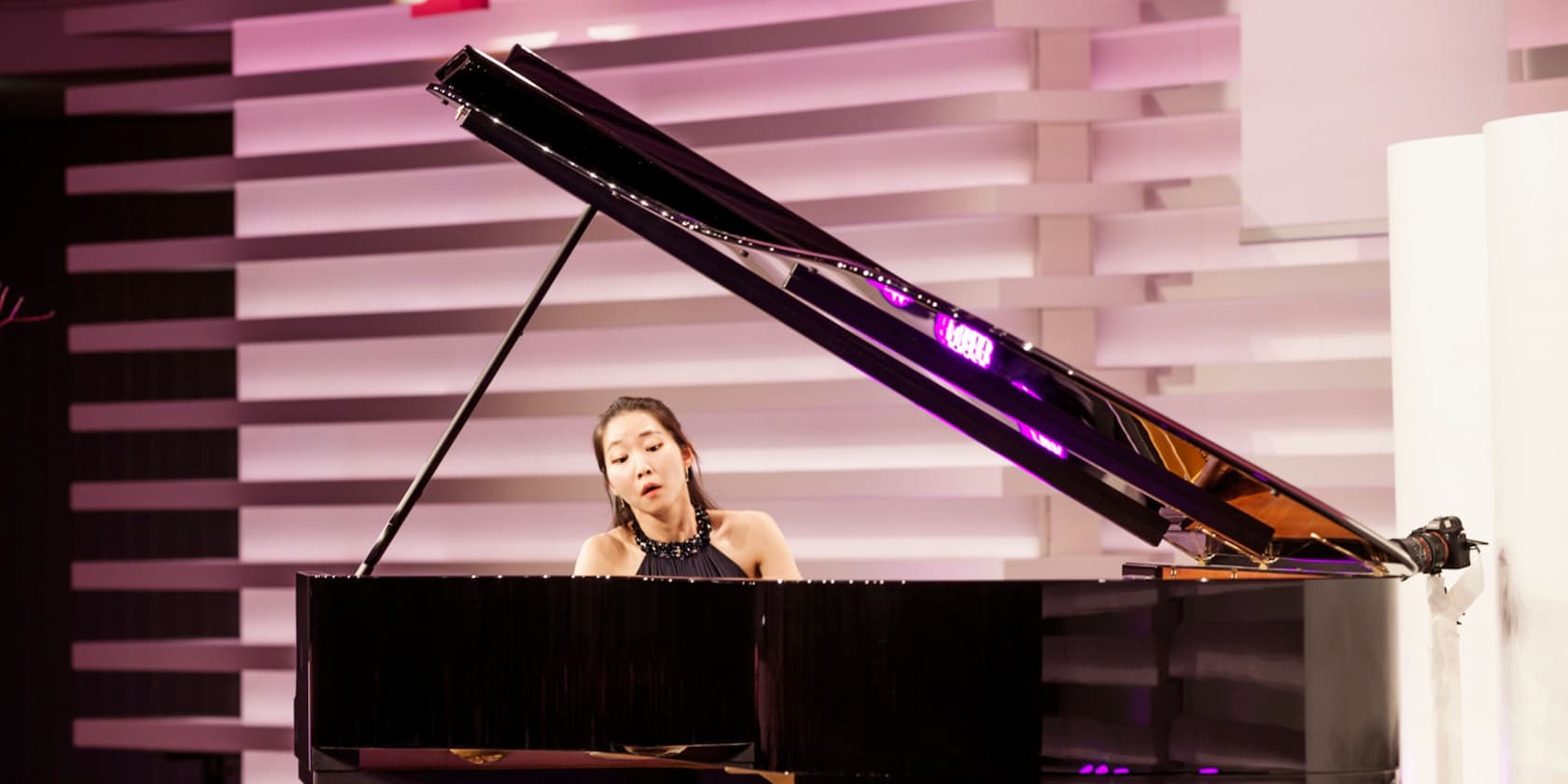 A woman playing a grand piano on a stage.