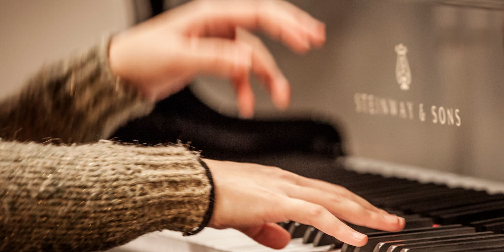 Hands playing the keys of a Steinway & Sons piano