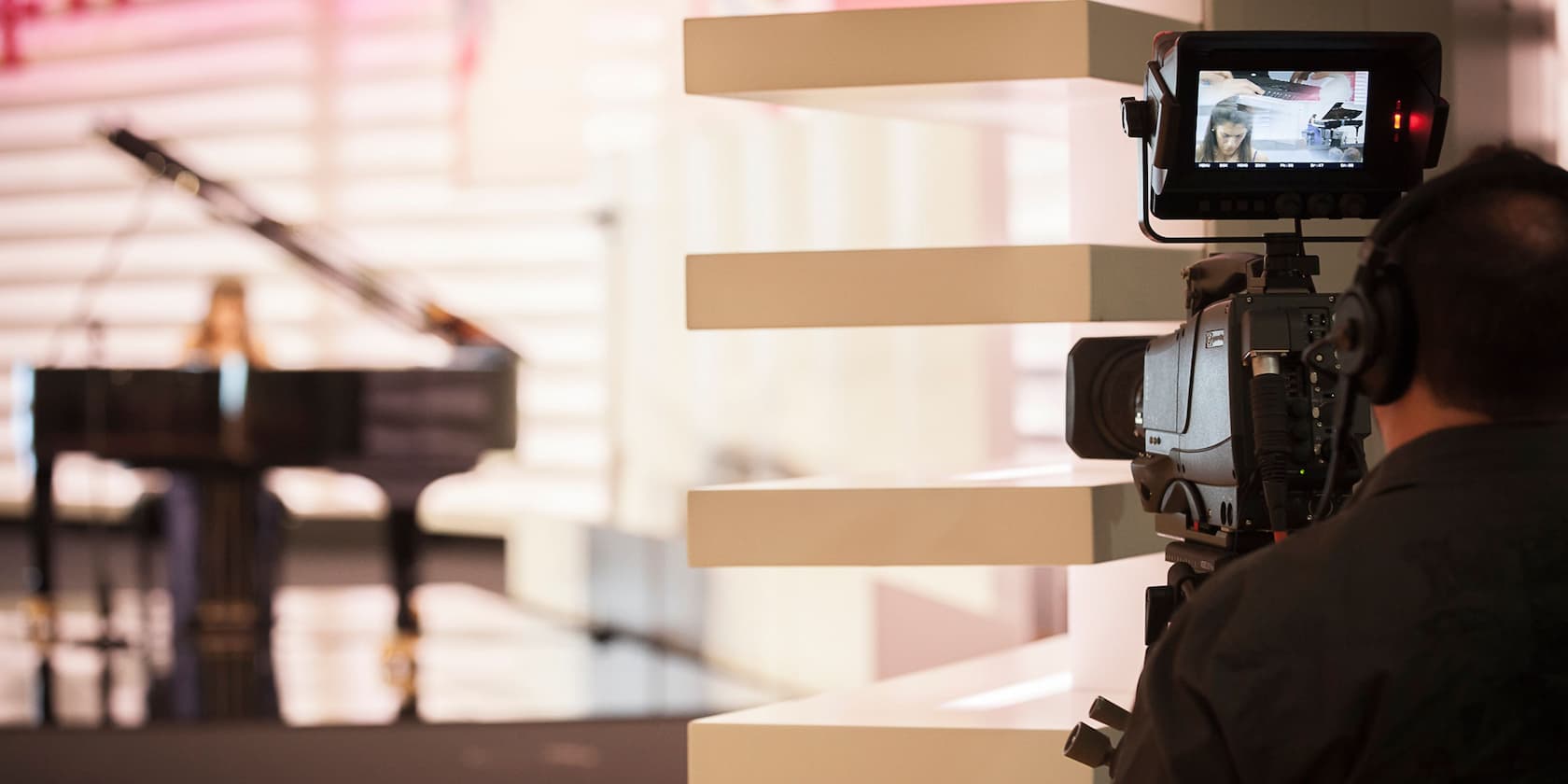 Cameraman filming a woman at a piano