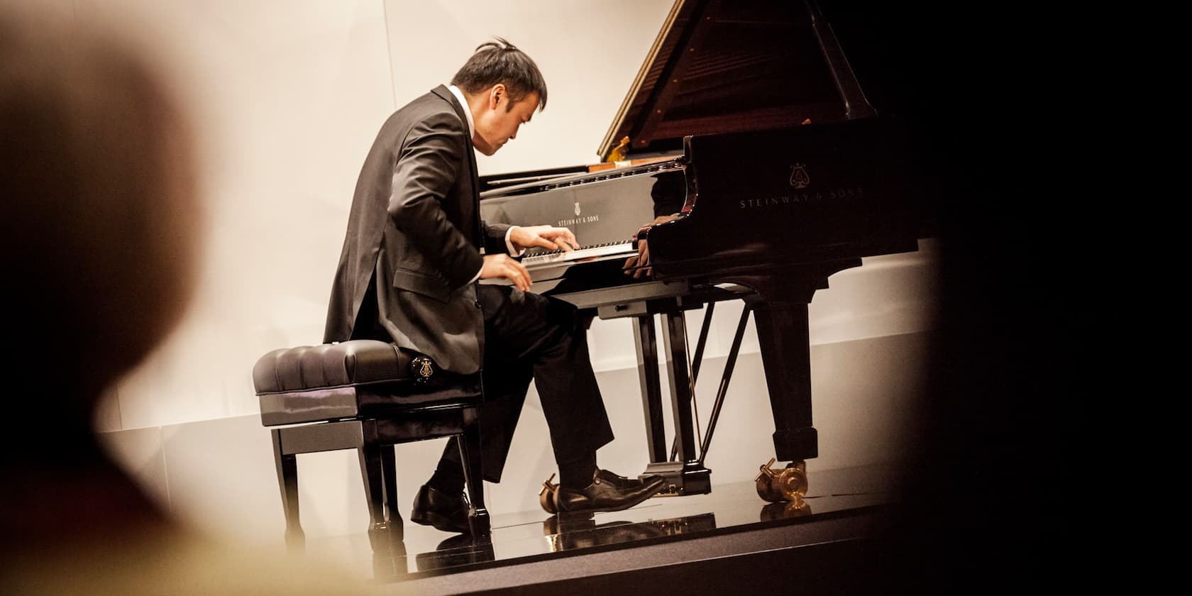 A pianist plays a piano at a concert.