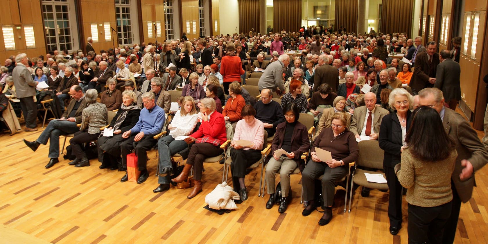 Eine große Menschenmenge sitzt in einem Konferenzraum.