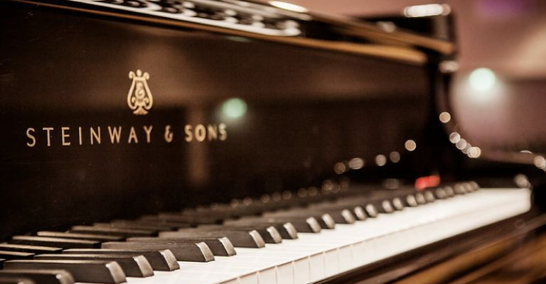 Close-up of a Steinway grand piano with keyboard in foreground.