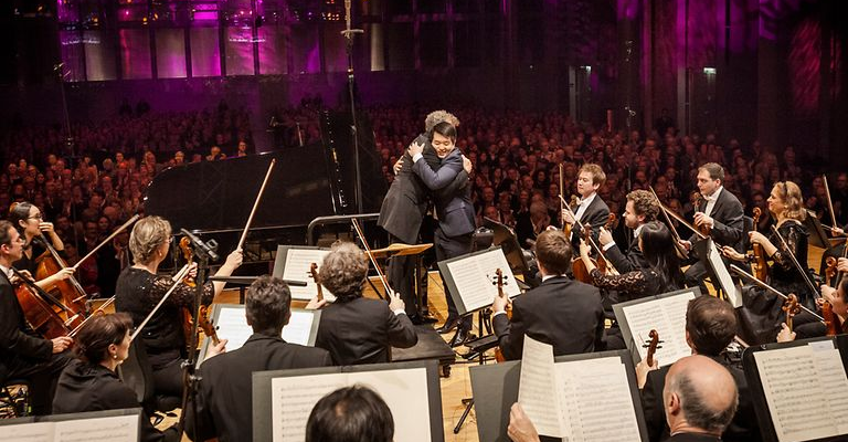 conductor embraces piano player on stage