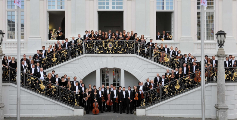 Beethoven Orchestra members in evening attire arranged on staircase.