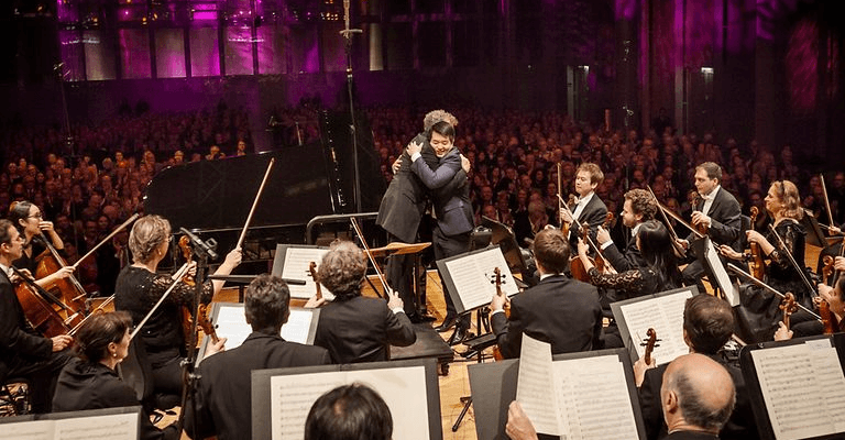 conductor embraces piano player on stage